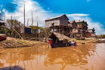 Kampong Phluk floating fishing village, boats and houses on stilts on rural river in drought season. Tonle Sap lake, life and work cambodian people, residents poverty country Cambodia. Copy text space - obrazy, fototapety, plakaty