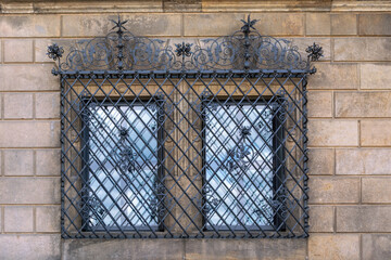 Two rectangular windows. Closed with a figured iron lattice on the background of a stone wall. From the Windows of the world series.