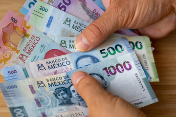 Mexico, Bundle of pesos banknotes held in hands, Financial concept, Mexican business success - obrazy, fototapety, plakaty