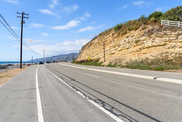 Curve along a coastal highway running at the foot of a cliff on a clear autumn day. California, USA.