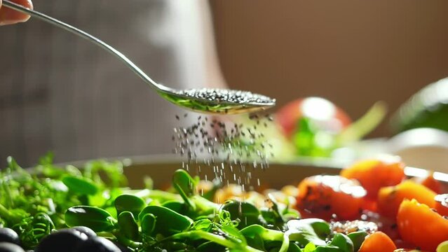 slow motion video of chia seeds falling into the bowl. healthy bowl recipes with vegetables and heart-healthy fat or Omega-3 fatty acids. avocados, tomato, olives, broccoli and chickpeas close up 