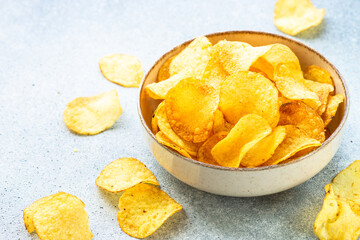 Potato chips in wooden bowl on white table. Top view with copy space.