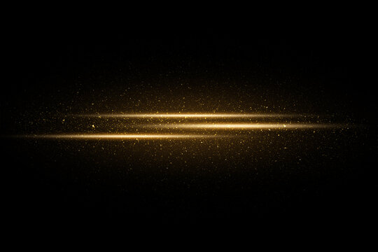 Golden sparkles and glitter on black background. Gold particles and flash of light rays on dark background