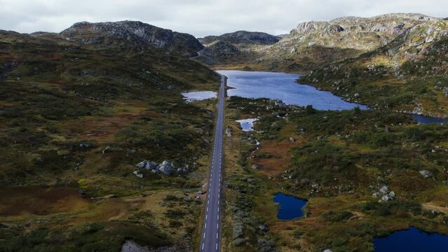 Amazing aerial shot of Norwegian landscape, mountain lakes and forest, road in middle. Telemark county in western Norway. Drone shot of national park
