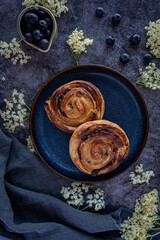 Freshly baked pain aux raisins with berries ob dark background 
