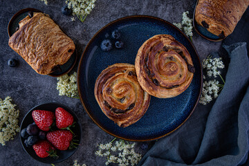 Freshly baked pain aux raisins with berries ob dark background 