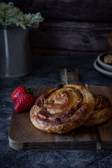 Freshly baked pain aux raisins with berries ob dark background 