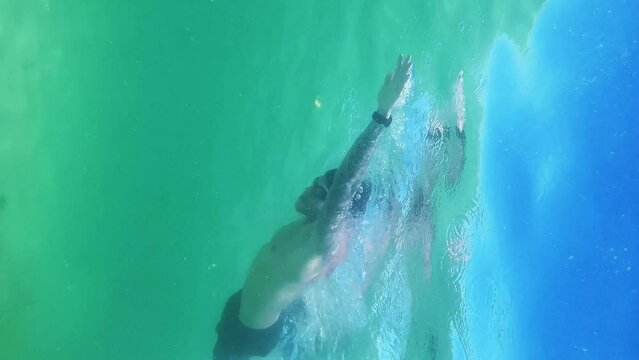Man wearing swimming goggles practicing swimming in the Maragogi sea, Brazil. Underwater view