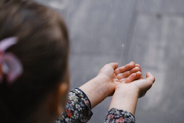 kids hands catching raindrops, weather concept. Closeup of rain falling in hands