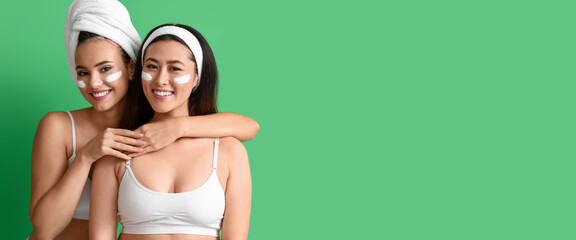 Beautiful young women with facial masks on green background with space for text