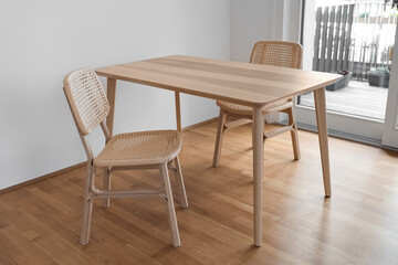 Wooden dining table with wicker chairs in light room