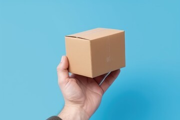 Hand holding cardboard box on blue background, hand with package, Generative AI
