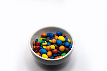 Colorful chocolate in a bowl isolated on white background.
