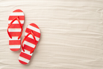 An aerial glimpse of summer bliss. Red and white striped flip-flops rest harmoniously on the sandy...
