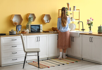 Woman standing on stylish rug in modern kitchen