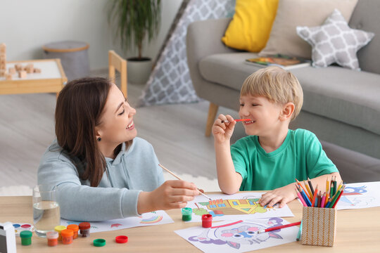 Nanny with little boy drawing at home