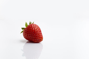 Ripe juicy strawberries with leaves on white background with reflection on the table and space for text