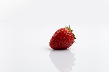 Ripe juicy strawberries with leaves on white background with reflection on the table and space for text