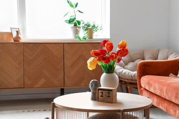 Vase with beautiful tulip flowers on coffee table in interior of living room