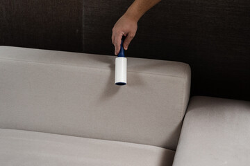 Process of cleaning couch using lint roller from cat and dog hair. Cleaner is removing lint from...