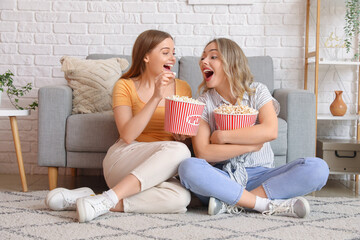 Young sisters eating popcorn at home