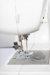 Modern white sewing machine presser foot closeup, macro. Sewing equipment, work tool for atelier business, manufacturing, occupation.