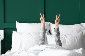 Morning of young woman showing victory gesture in bed