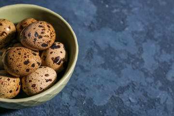 Bowl with fresh quail eggs on blue background, closeup