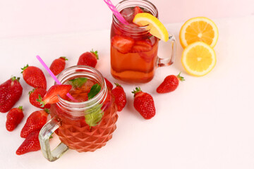 Mason jars of tasty strawberry drink on white background