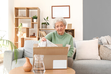 Senior woman opening parcel at home