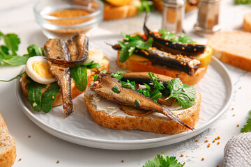 Plate of tasty sandwiches with canned smoked sprats on table
