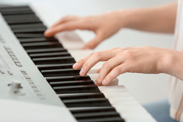 Young female musician playing  synthesizer, closeup