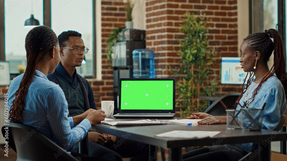 Poster workers using laptop with green screen in coworking space, meeting to discuss new business vision in