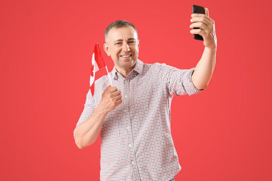 Mature man with flag of Canada taking selfie on red background - Powered by Adobe