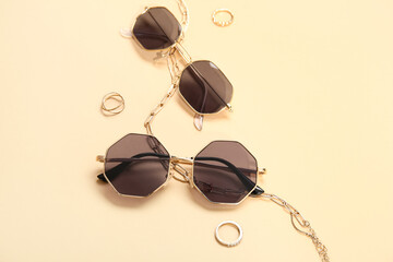 Stylish sunglasses and jewellery on beige background