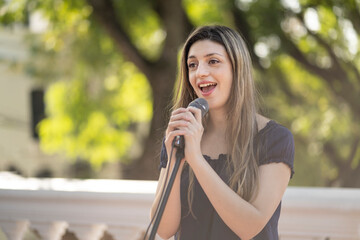 Young blonde woman singing in the street. Singer performing in the street.