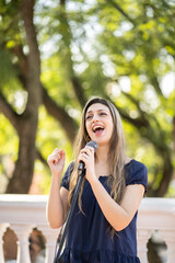 Fototapeta premium Young blonde woman singing in the street. Singer performing in the street.