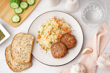Cutlets with bulgur and boiled vegetables on light table in kitchen