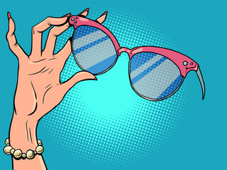 Shop for womens jewelry and glasses. Female hand with manicure holds sunglasses.