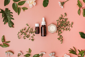 essential serum or skincare product with natural green leaves and flowers on a beauty background.