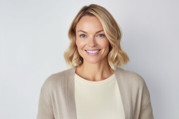 Obraz premium happy woman in beige sweater over grey background, smiling at camera