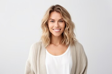 Portrait of beautiful female with blond hair and natural make-up, looking at camera and smiling, standing over white background