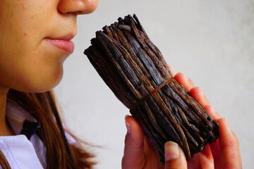 Close up of a girl holding vanilla beans in her hands and enjoying its aroma