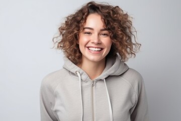 Portrait of a smiling young woman in hoodie on grey background