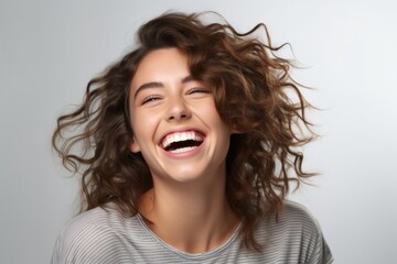 Portrait of beautiful young woman with flying hair on grey background.