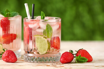 Glasses of strawberry lemonade on white wooden table outdoors
