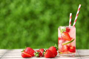 Glass of strawberry lemonade on grey tile table outdoors