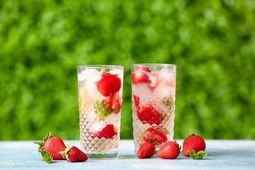 Glasses of strawberry lemonade on blue table outdoors