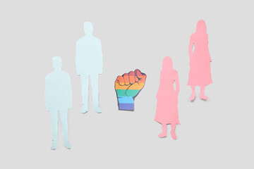 Paper fist with human figures on light background. LGBT concept