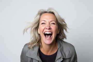 Portrait of a happy woman laughing and looking at camera over gray background